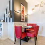 Dining area with red chairs and table, wall decor and cabinet