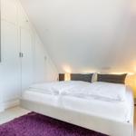 Bedroom with double bed, white wardrobes, and purple rug.