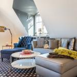 Living room with sofa, armchair, and table under sloped ceiling.