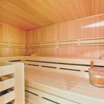 Sauna with wooden benches and bucket with ladle.