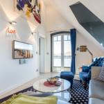 Living area with sofa, armchair, and TV under sloped ceiling.