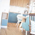 Dining area with wooden floor and blue kitchen in the background.