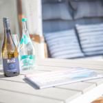 Table with wine bottle, water, and brochure on an outdoor terrace.