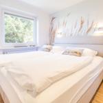 Bedroom with large bed, window and wall mural of reeds.