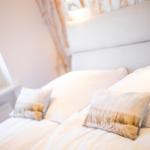 A bed with white sheets and pillows, a window, and a headboard.