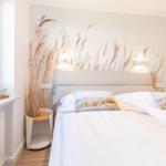 Bedroom with bed, wall mural, and window. A wooden object is on the windowsill.
