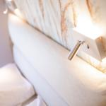 Bed headboard with modern wall lamp and decorative wallpaper.