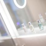 Mirror with illuminated frame and bottles on glass shelf