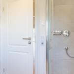 Shower with glass enclosure, showerhead, and wall-mounted heater.