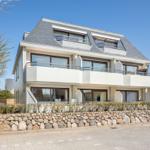 Modern villa with balconies and stone wall. Large windows and dormer windows.