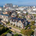 Haus mit Solaranlagen und Garten, Blick auf Stadt und Meer.
