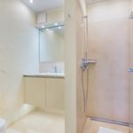 Badezimmer mit Dusche, Waschbecken und Toilette. Wandbild mit Pflanzenmotiv.