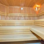 Holzsauna mit mehreren Sitzbänken und einem Eimer.
