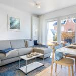 Wohn- und Essbereich mit Sofa, Tisch und Blick auf Balkon.