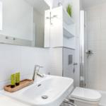Badezimmer mit Waschbecken, Spiegel, Dusche und Toilette.