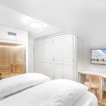Schlafzimmer mit Doppelbett, Sauna, Kleiderschrank und Schreibtisch mit TV.
