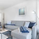 Wohnzimmer mit grauem Sofa, blauem Teppich und Stehlampe.