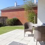 Terrace with table and chairs, lawn area, and red brick wall in the background.