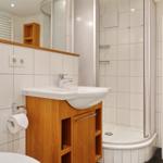 Bathroom with sink, shower, and wooden cabinets.