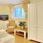 Bedroom with bed, wardrobe, armchair, and TV.