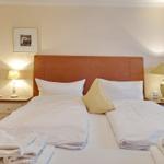 Double bed with white linens, two nightstands with lamps, and a picture on the wall.