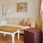 Living room with cream sofa, wooden table, and patterned ottoman.