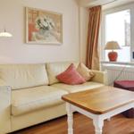 Living room with cream sofa, wooden table, and windows with curtains.