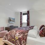 Bedroom with bed, TV, and window with curtains.