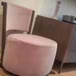 A pink seating area with wooden frame stands in front of a cabinet.