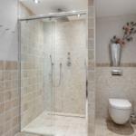 Shower with glass enclosure, toilet, and wall decor with flowers.