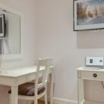 Desk with chair, mirror, lamp, and wall-mounted TV