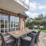 Terrace with dining table and chairs, view into the house and garden.