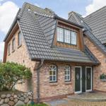 House with brick facade, dormer windows, and green front door.