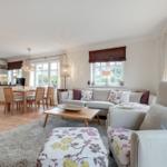 Living and dining area with kitchen and windows.