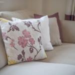 A sofa with cushions in floral patterns and neutral colors.