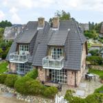 House with balconies, garden and stone walls. Terrace with table and chairs.