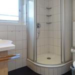 Badezimmer mit Dusche, Waschbecken und Toilette. Fenster sorgt für Tageslicht.