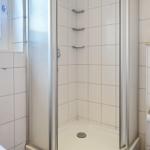 Badezimmer mit Duschkabine, Waschbecken und Toilette.
