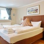 Schlafzimmer mit Bett, Nachttisch und Fenster mit Vorhängen.
