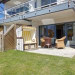 Hinterhof mit Garten, Liegestuhl und Terrasse mit Sitzgelegenheiten.