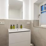 Bathroom with sink, mirror, and window with blinds.