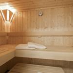 Wooden sauna with multiple benches and a thermometer on the wall.