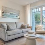 Living room with sofa, armchair, and large windows.