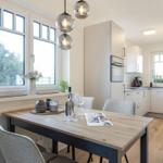 Dining area with table, chairs, and view of the kitchen.