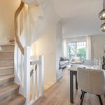 House with dining area, living area, and wooden staircase with curved handrail.