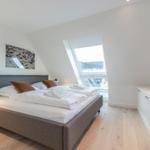 Bedroom with skylight, bed, nightstand, and TV.