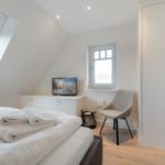 Bedroom with skylight, bed, wardrobe, and chair.