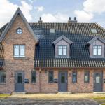 Two-family house with brick facade and dormers. Three entrances and dark windows.