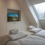 Zimmer mit Dachfenster, Bett und TV in Einbauschränken.