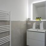 Badezimmer mit Waschbecken, Spiegel und Handtuchhalter.